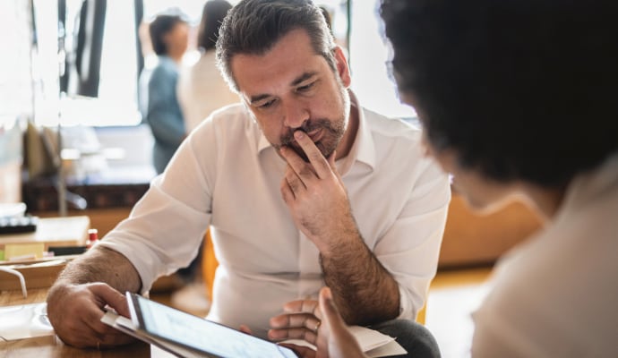Uomo che guarda un altro uomo che sta usando un computer portatile